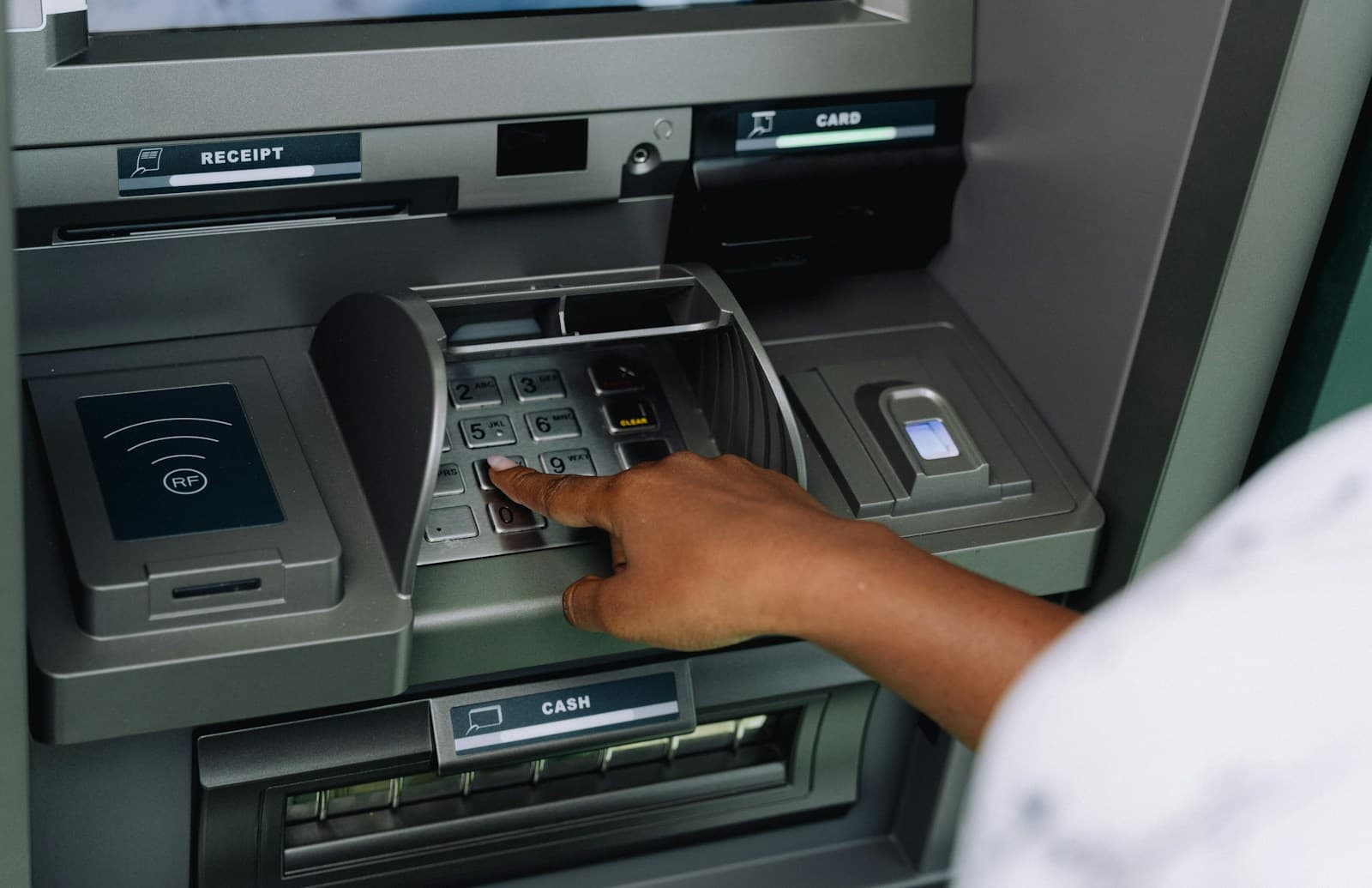 Une personne utilise un distributeur automatique de billets installé en façade.